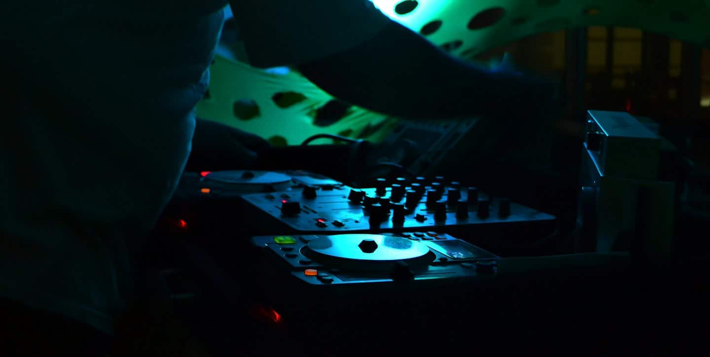 DJ che mixa musica su una console illuminata con luci brillanti.